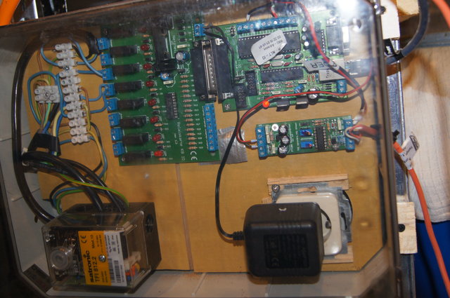 Steuerung<br />Die Steuerung ist in einem spritzwassergeschützten Standardgehäuse (IP64) untergebracht.<br />Verwendet wird ein AVR Net-IO Board mit originärem OS. <br />Für die Relaissteuerung wird ein eigenes Zusatzboard von AVR verwendet (Platine links im Bild).<br />Wir hatten Abweichungen in der Temperaturmessung. Daher verwenden wir einen zusätzlichen Messverstärker (kleine Platine rechts im Bild).<br />Mit diesem Verstärker liefert der Fühler (PT100) einwandfreie und akurate Messwerte. <br />Ein Herzstück ist der Gasfeuerungsautomat (GFA) von Satronic (vormals Hersteller Honeywell).<br />Der GFA übernimmt die Flammensteuerung und ist sehr robust (hat alle Fehlversuche klaglos überstanden).<br />Auch auf dem Bild zu sehen ist das rote PT100-Kabel, das in den Maischetopf reicht.<br />Ebenfalls gut erkennbar das Anschlusskabel (Cross-over) für unser Notebook.