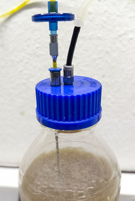 Hier ist noch mal die Kappe der Laborflasche zu sehen. Der linke Fitting dint als Durchführung für die Kanüle, welche fast bis zum Boden der Glasflasche geht. Der  Rechte  Fitting ist für die ausstömende überschüssige Luft.